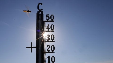 Die Sonne scheint hinter einem Thermometer. Symbolbild zur Bauernregel, die am Siebenschläfertag das Wetter für den Sommer vorhersagen soll.