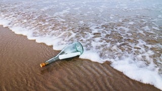 Eine Flasche mit Brief wird am Strand angespült (Symbolbild).