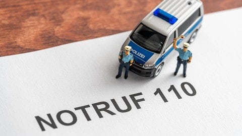 Polizeifiguren stehen auf einem Papier mit der Aufschrift "Notruf 110".