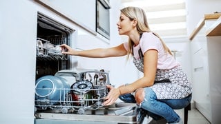 Junge Frau lacht: Sie kennt jeden Lifehack und kann die Spülmaschine richtig einräumen!