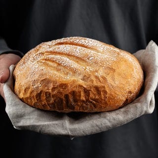 Ein Bäcker hält ein gutes Brot aus der Bäckerei in den Händen, so kann man es erkennen.