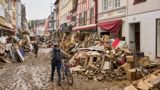 Ahrweiler: Eine Frau schiebt ihr Fahrrad durch den Schlamm.