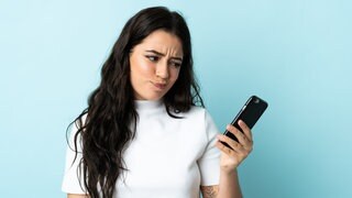Frau versucht mit dem Telefon einen Arzttermin zu bekommen (Symbolbild)