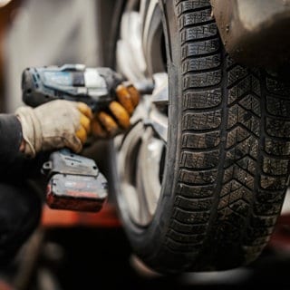 Jemand montiert in der Werkstatt Winterreifen auf ein Auto – was ist der Unterschied im Vergleich zu Allwetterreifen?