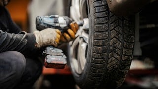 Jemand montiert in der Werkstatt Winterreifen auf ein Auto – was ist der Unterschied im Vergleich zu Allwetterreifen?