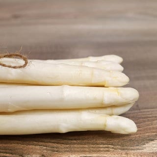 Ein Bund weißer Spargel vor dem Essen auf einem Holzbrett.